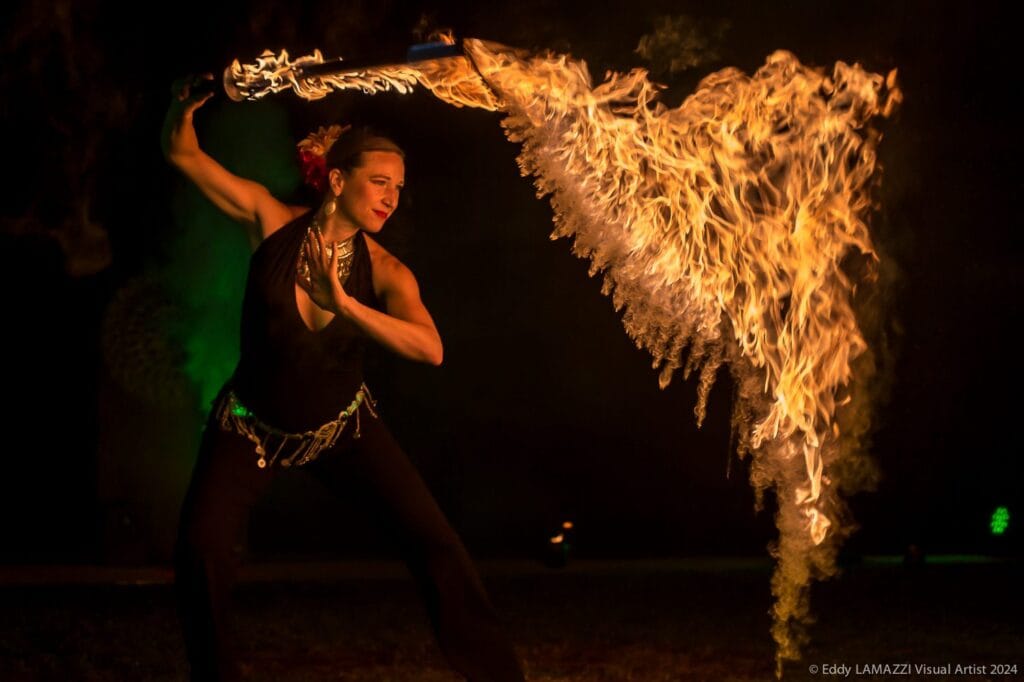 Une artiste de feu devant une gerbe de flammes lors d’un spectacle Ardensia