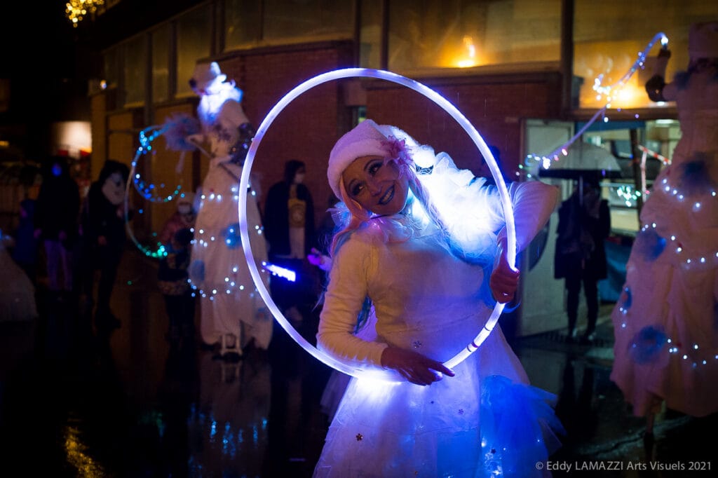 Une artiste de Féérie avec un cerceau lumineux, de nuit