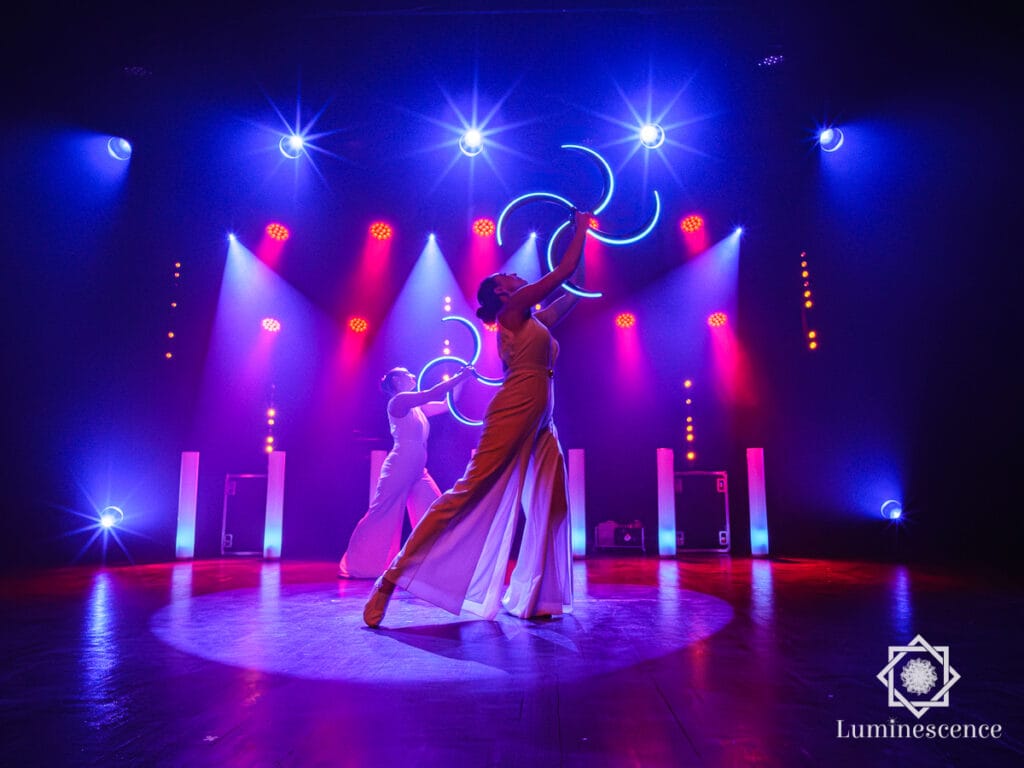 Une artiste avec un cerceau LED sur une scène éclairée en bleu, spectacle Symphonie