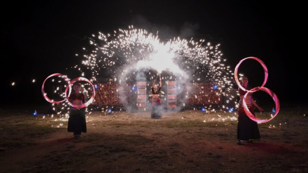 Artistes de Nomade avec des cerceaux devant une pluie d’étincelles, de nuit