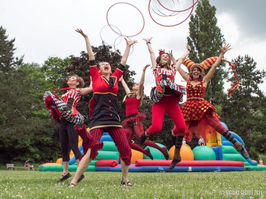 Artistes de Cirk’n’Swing avec des cerceaux dans un parc, devant une structure gonflable