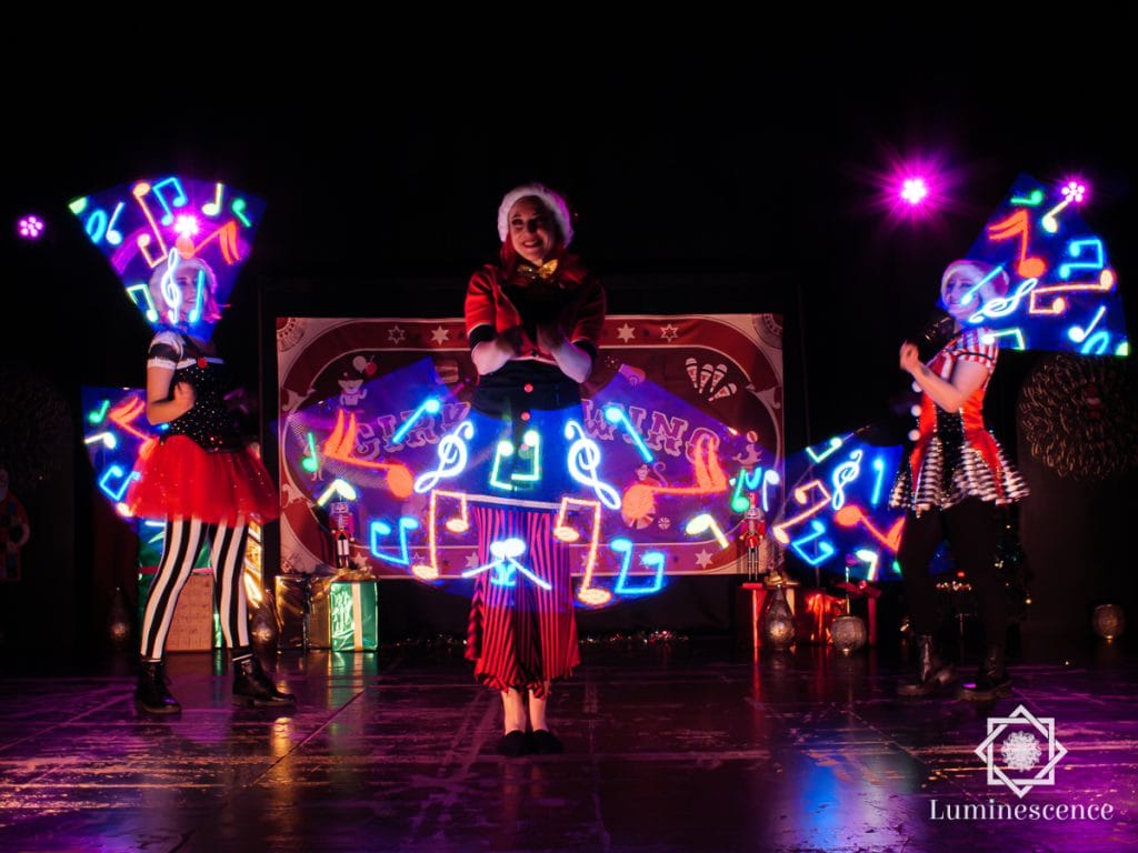 Artistes avec des accessoires LED lumineux devant un décor sur scène